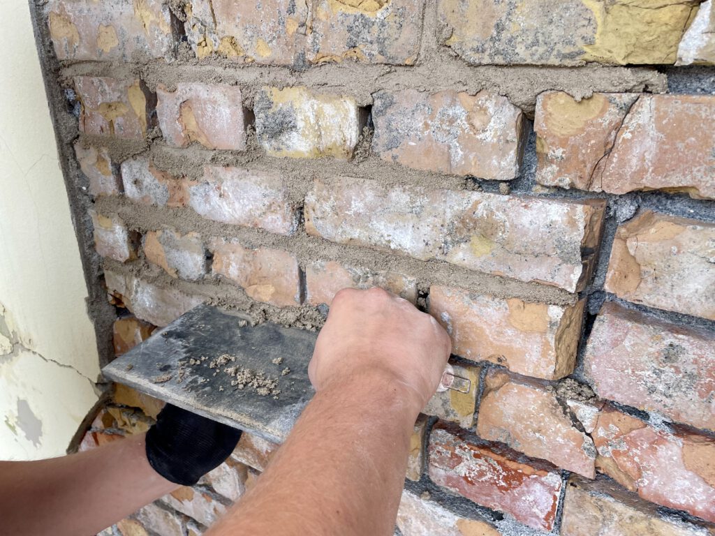 Mauerwerk wird ausgebessert mit Fugenmörtel.
